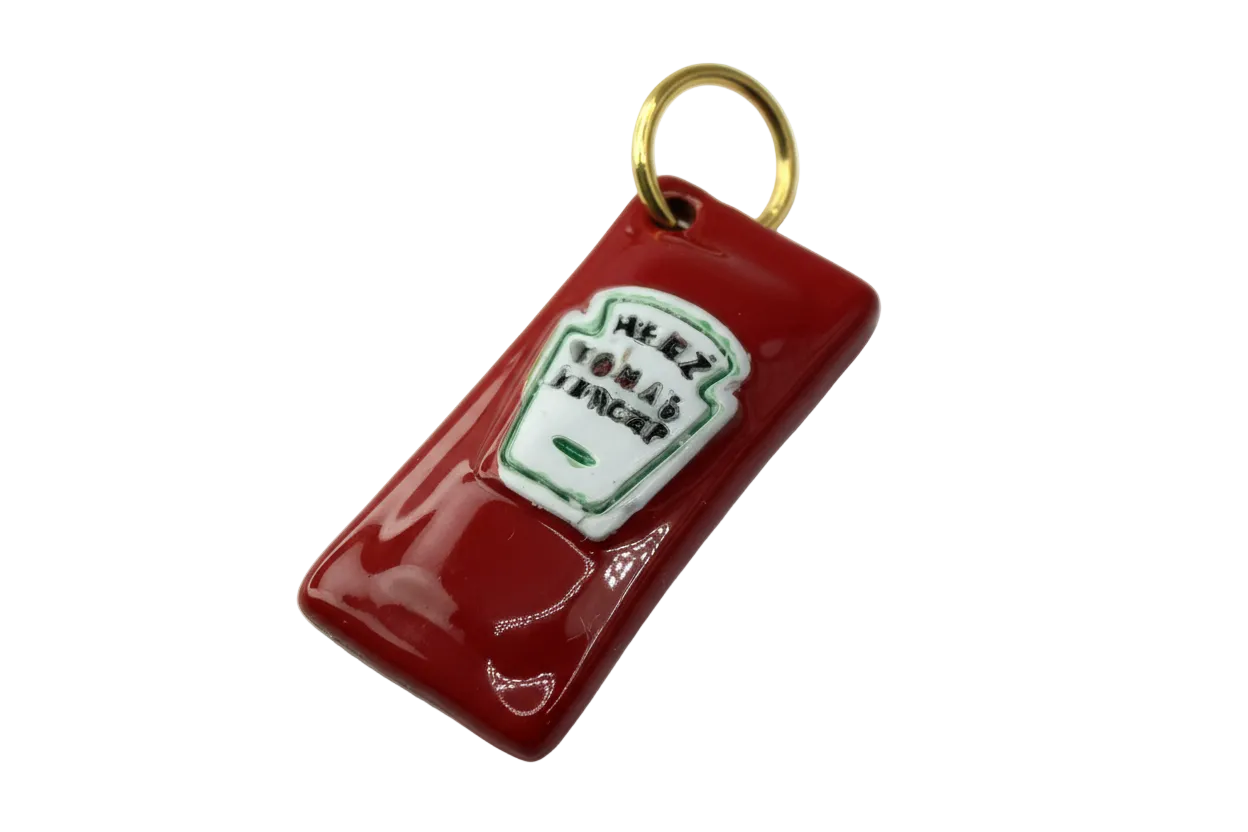 Glossy red ketchup bottle charm with raised white label, green outline, and gold top