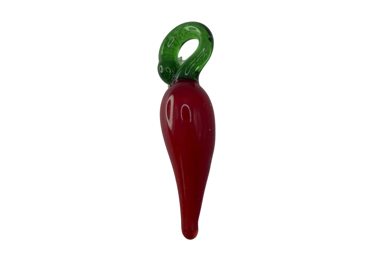 Red glossy chili pepper with translucent green stem on gold-toned base