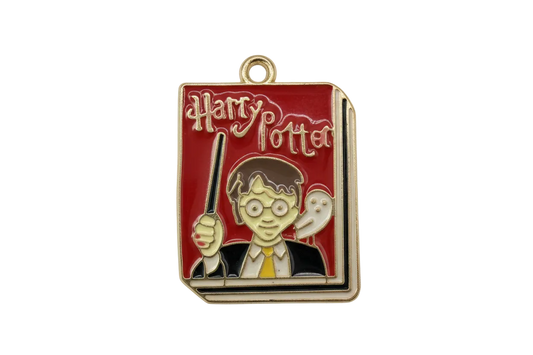 Red enamel book cover with gold lettering, young wizard with glasses holding a wand, and a white owl accent