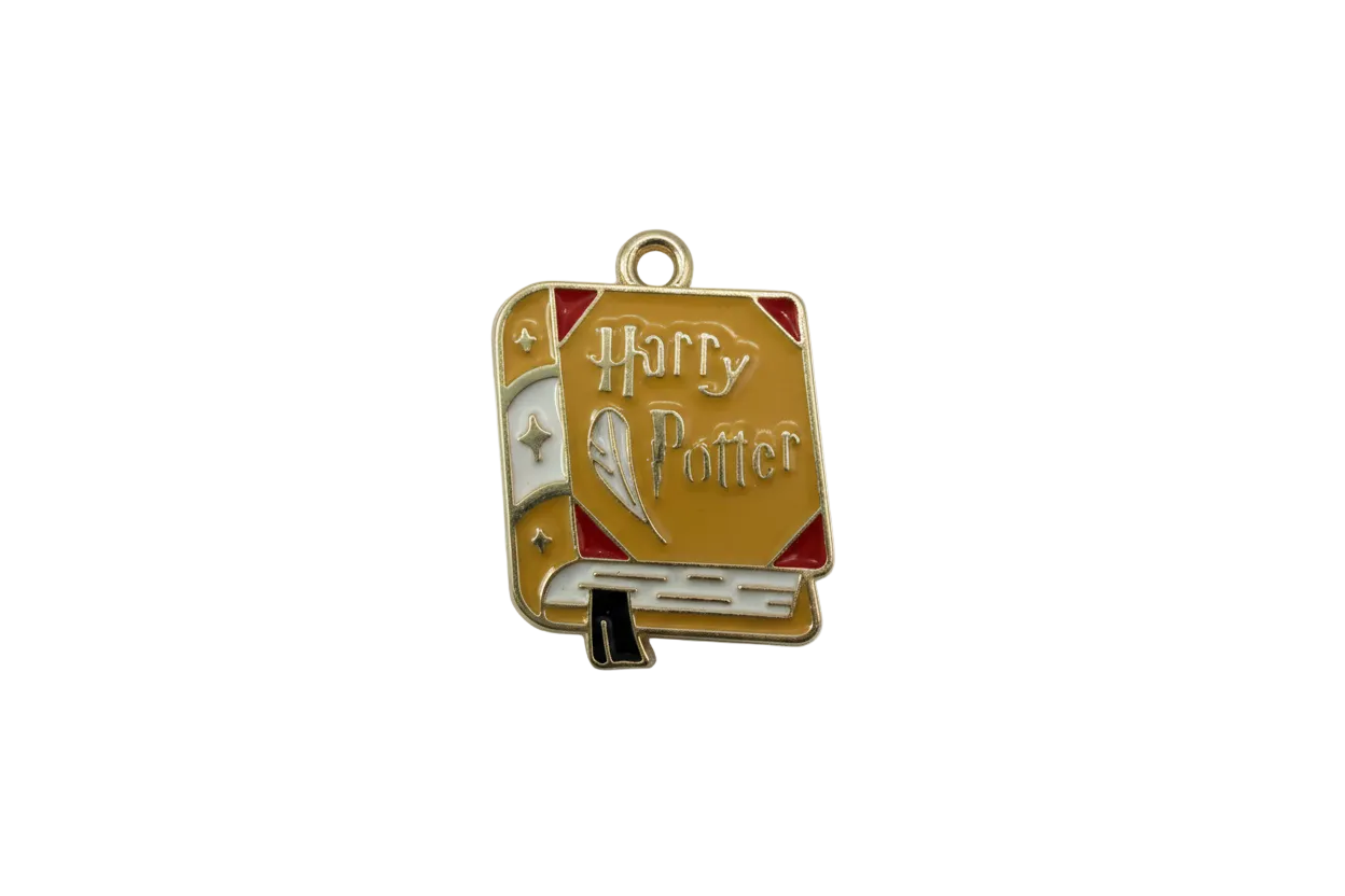 Mustard enamel spellbook with quill detail and red corners, gold-toned