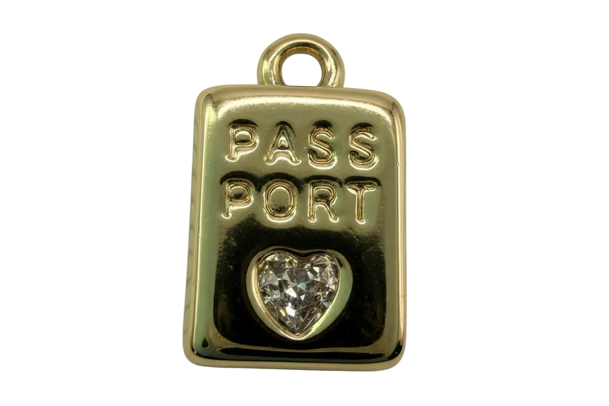 Gold passport tag with raised PASS PORT lettering and a clear heart-shaped faceted gem