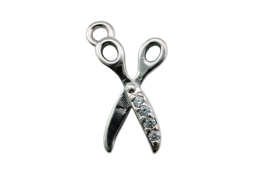 Polished silver scissors charm with clear pavé crystals on one side, isolated on black