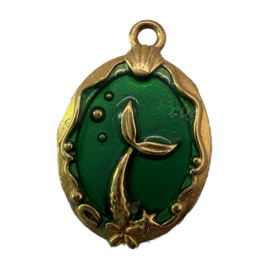 Oval gold medallion with emerald green enamel and raised mermaid tail, shell, and starfish details