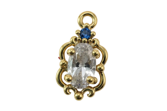 Gold ornate frame with clear faceted oval gem and small blue gem accent