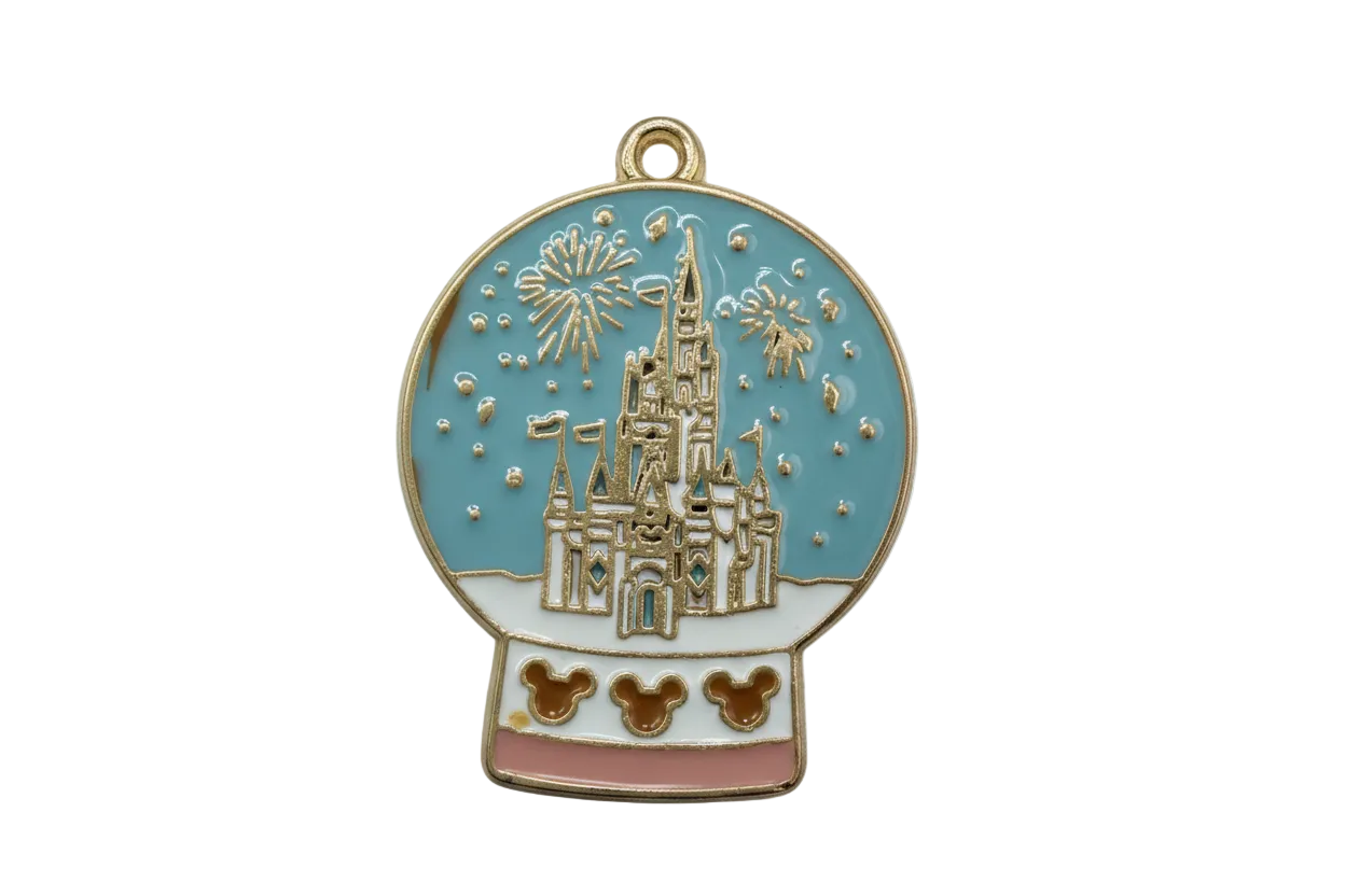 Gold enamel snow globe with blue sky, fairytale castle illustration, fireworks bursts, and blush base
