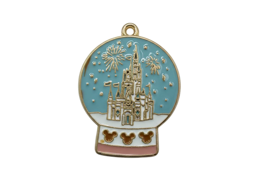 Gold enamel snow globe with blue sky, fairytale castle illustration, fireworks bursts, and blush base