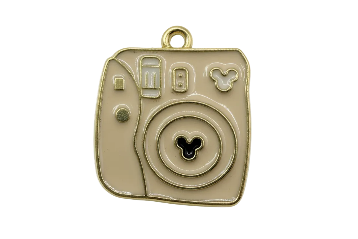 Glossy taupe enamel instant camera motif with gold outline and small black three-circle icon