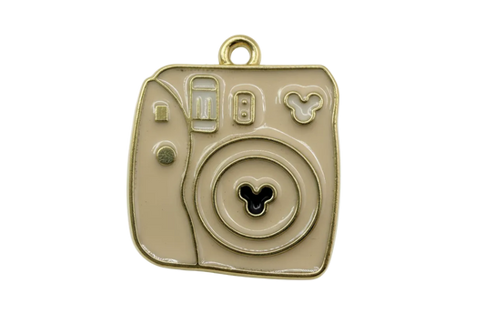 Glossy taupe enamel instant camera motif with gold outline and small black three-circle icon