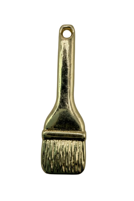 Glossy gold paintbrush charm with textured bristles and smooth handle