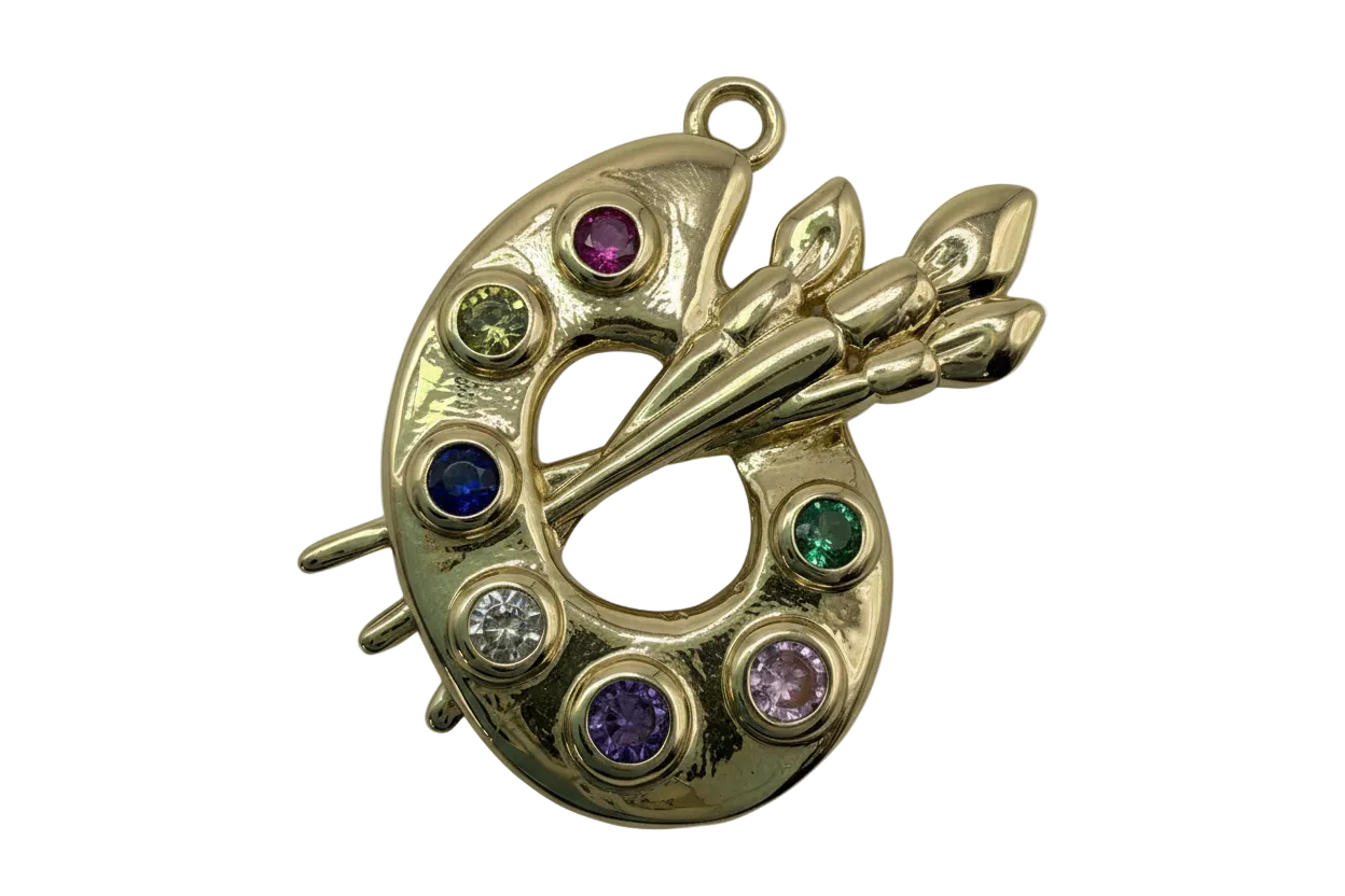 Gold artist paint palette with crossed brushes and multicolor round gems