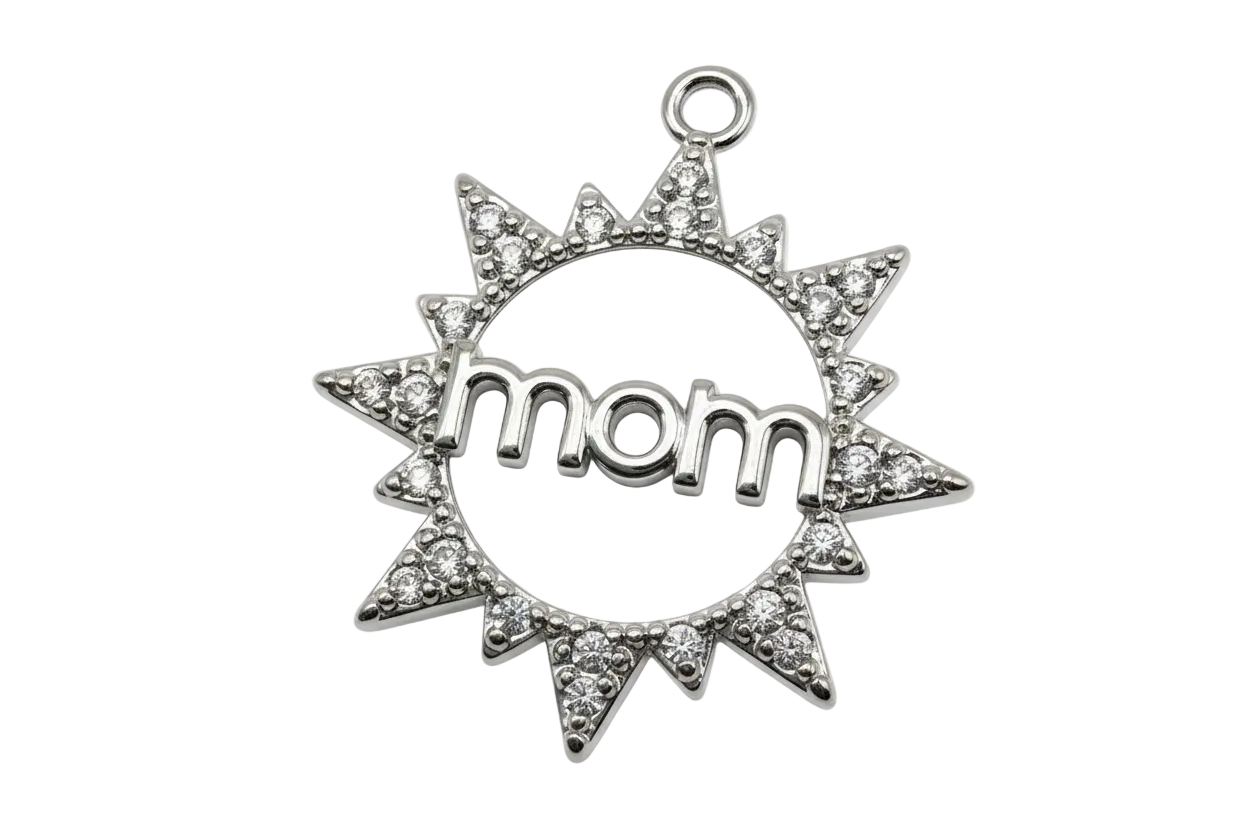 Silver sunburst medallion with clear crystals and raised “mom” over white patterned enamel