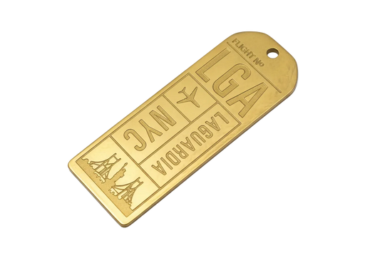 Gold engraved airport boarding pass tag with LGA and NYC lettering, airplane icon, and skyline motif