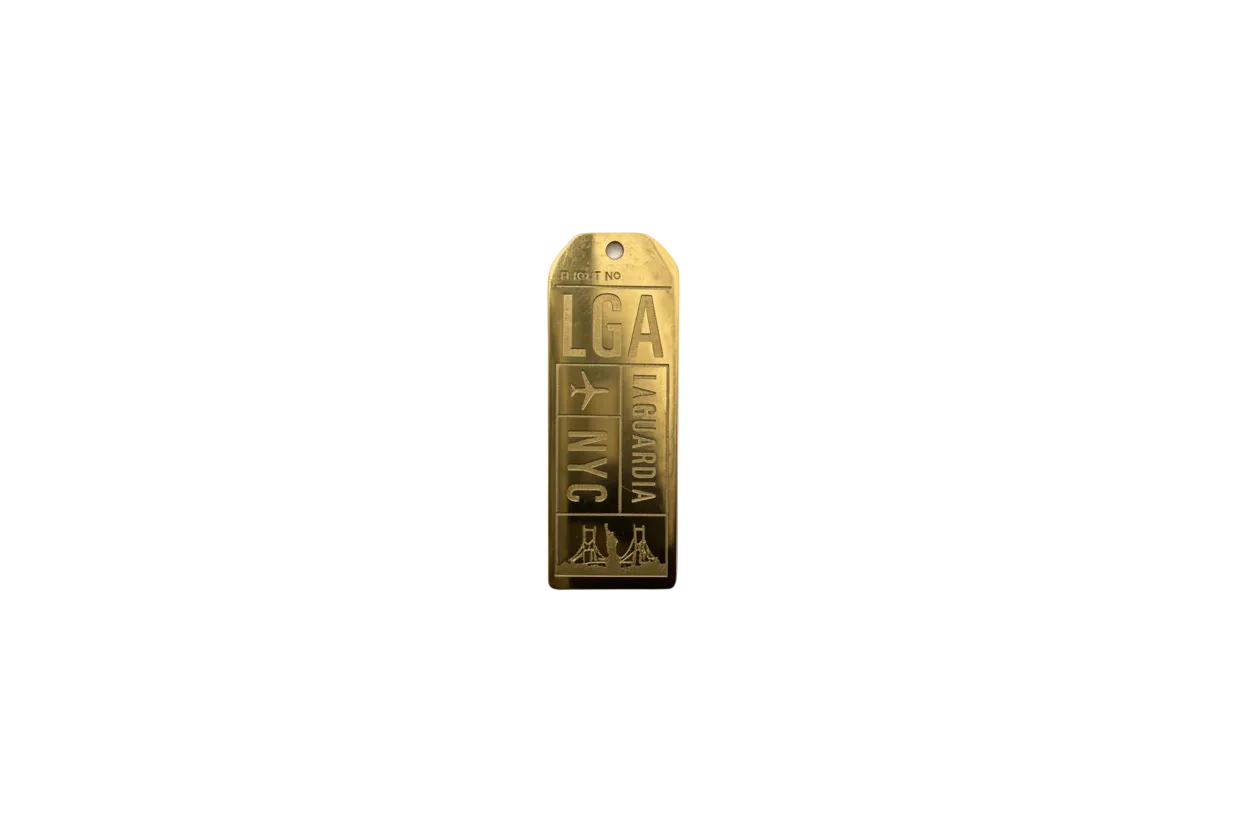 Gold engraved boarding pass tag with LGA/NYC, airplane and skyline
