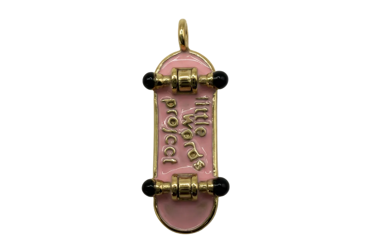 Glossy pink enamel skateboard with gold lettering and black wheels, gold-tone finish