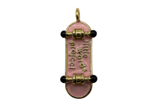 Glossy pink enamel skateboard with gold lettering and black wheels, gold-tone finish