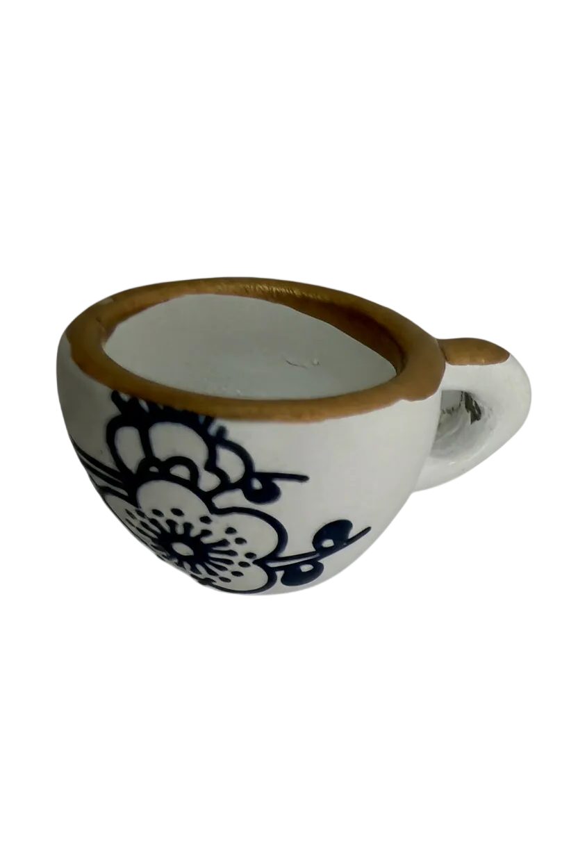 White oval piece with black lace floral design and gold edge, angled side view
