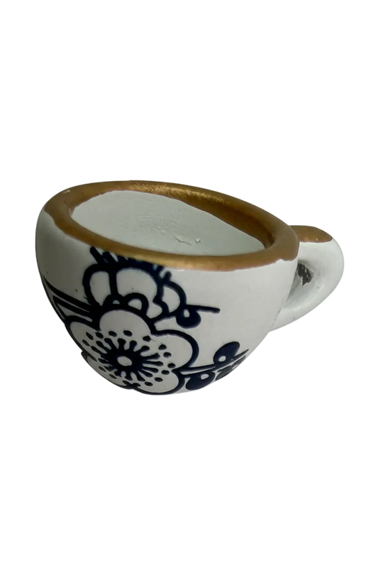 Glossy white porcelain teardrop with blue floral print and gold-toned rim