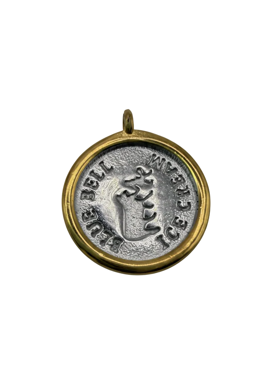 Two-tone round coin medallion with raised cow motif and stamped lettering, gold rim with antiqued silver center