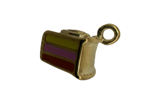 Gold cake slice charm with green, purple, and red enamel layers and a whipped cream top