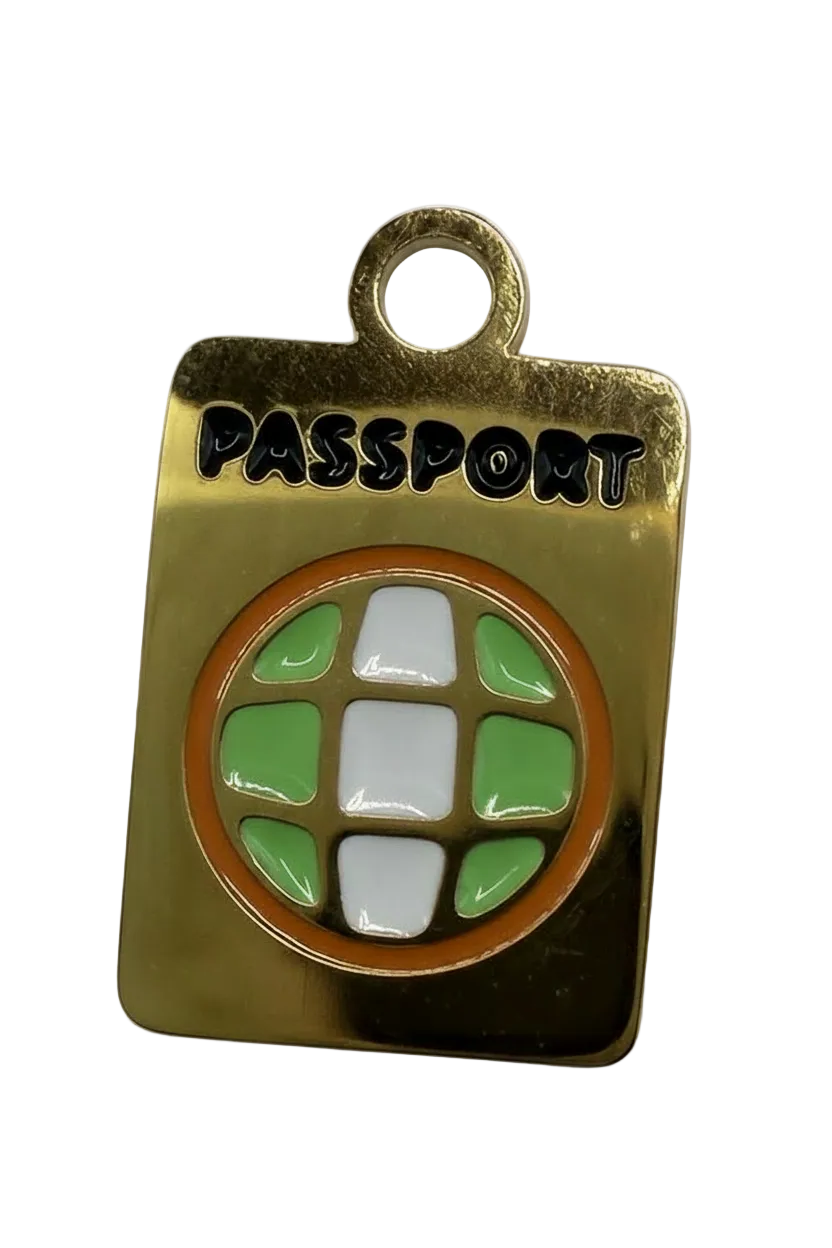 Polished gold rectangular tag with circular green and white enamel mosaic, orange border, and black lettering
