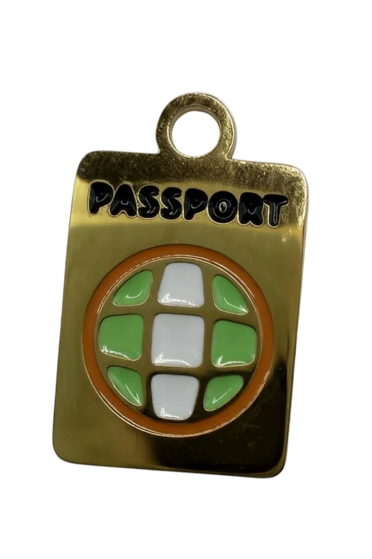 Polished gold rectangular tag with circular green and white enamel mosaic, orange border, and black lettering