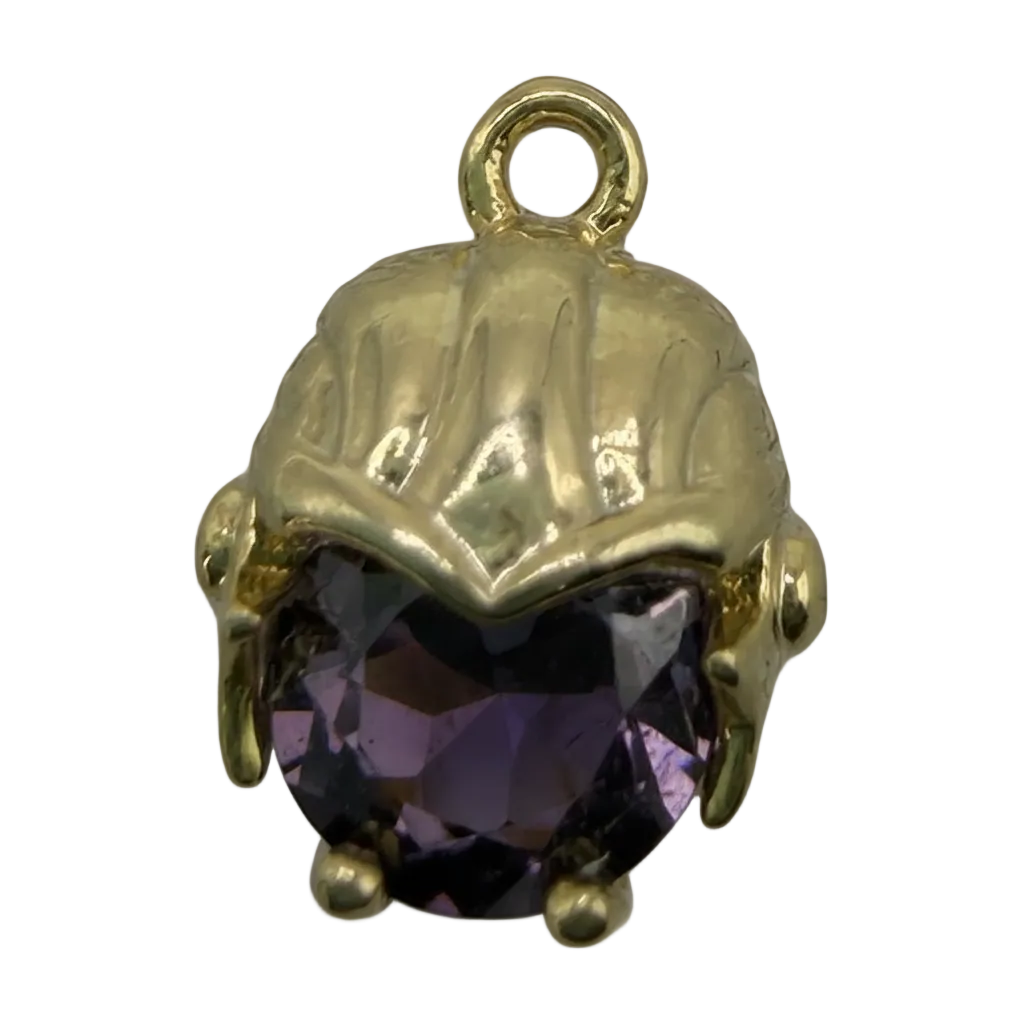 Polished gold scallop shell with a faceted deep purple gem, close-up on black background