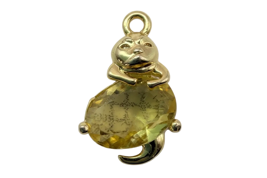 Polished gold teddy bear figure hugging a faceted yellow gem with subtle smoky marbling