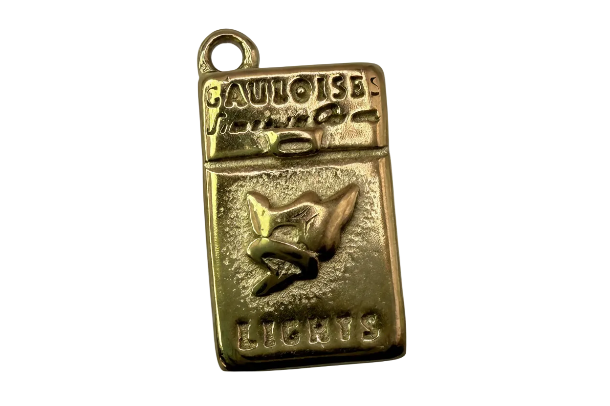 Gold rectangular cigarette pack charm with raised lettering and bird emblem