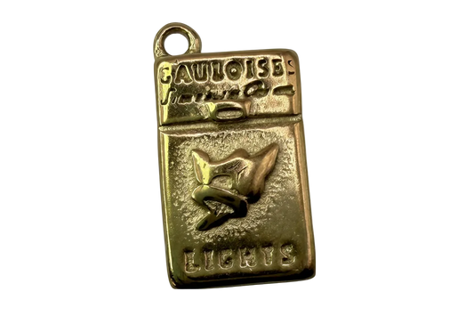 Gold rectangular cigarette pack charm with raised lettering and bird emblem