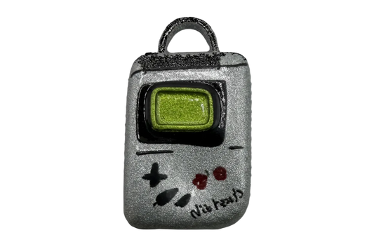 Silver retro handheld game console charm with green screen, black frame, and red buttons