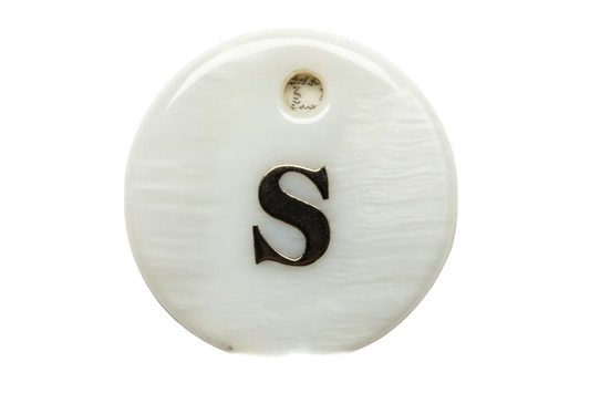 White round disc charm with polished gold letter S on an iridescent surface