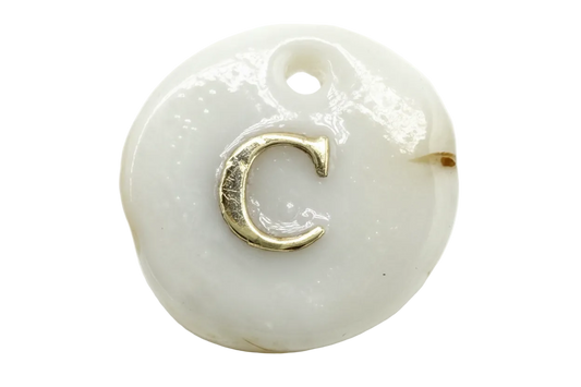 Glossy white round disc with raised gold letter C