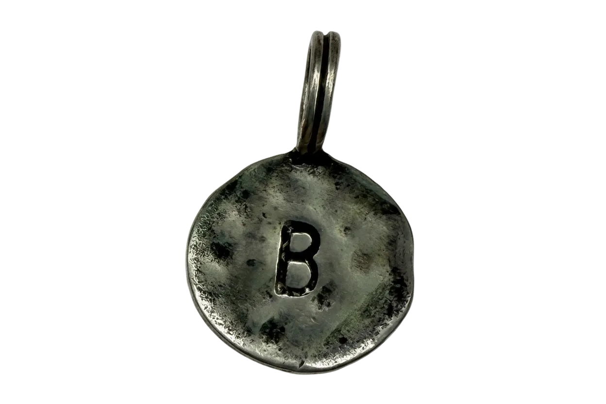 Antiqued silver round coin with raised letter B and darkened patina