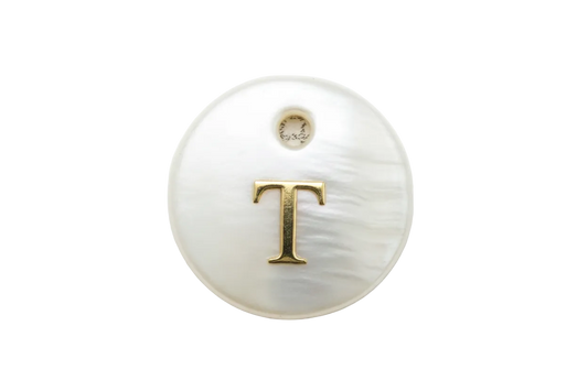 Pearl-white iridescent round disc with raised gold letter T