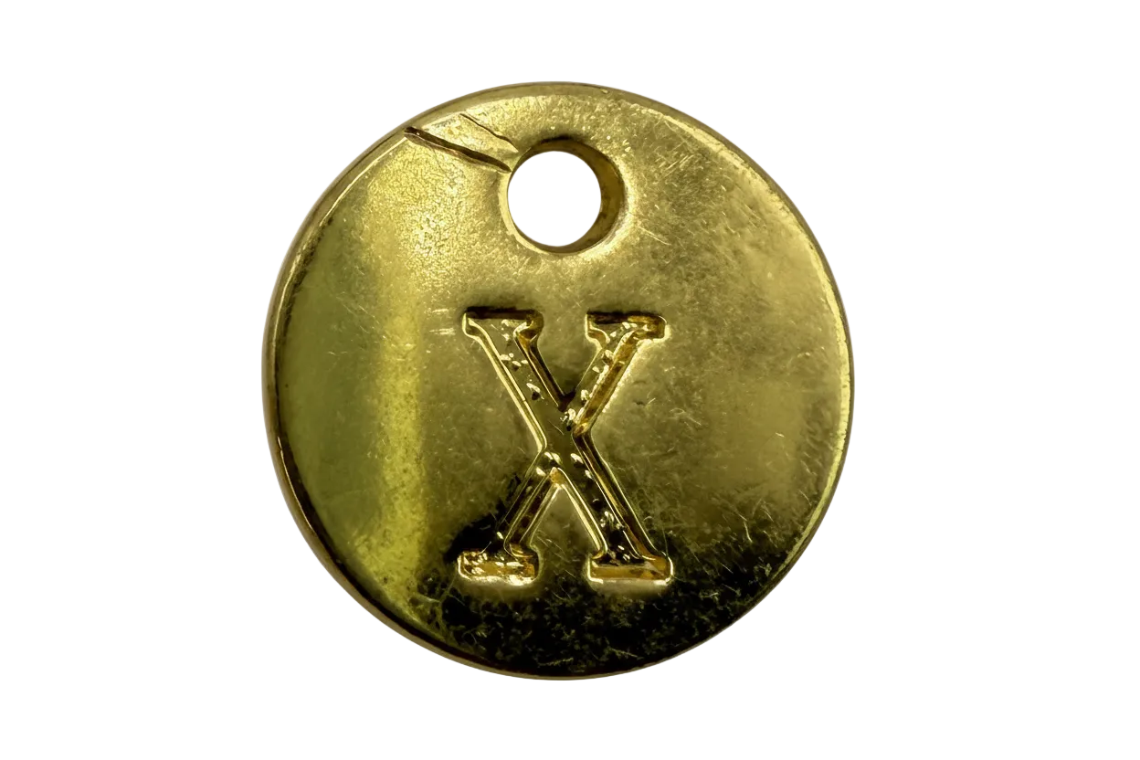 Gold round coin with raised letter X and small clear gem accent