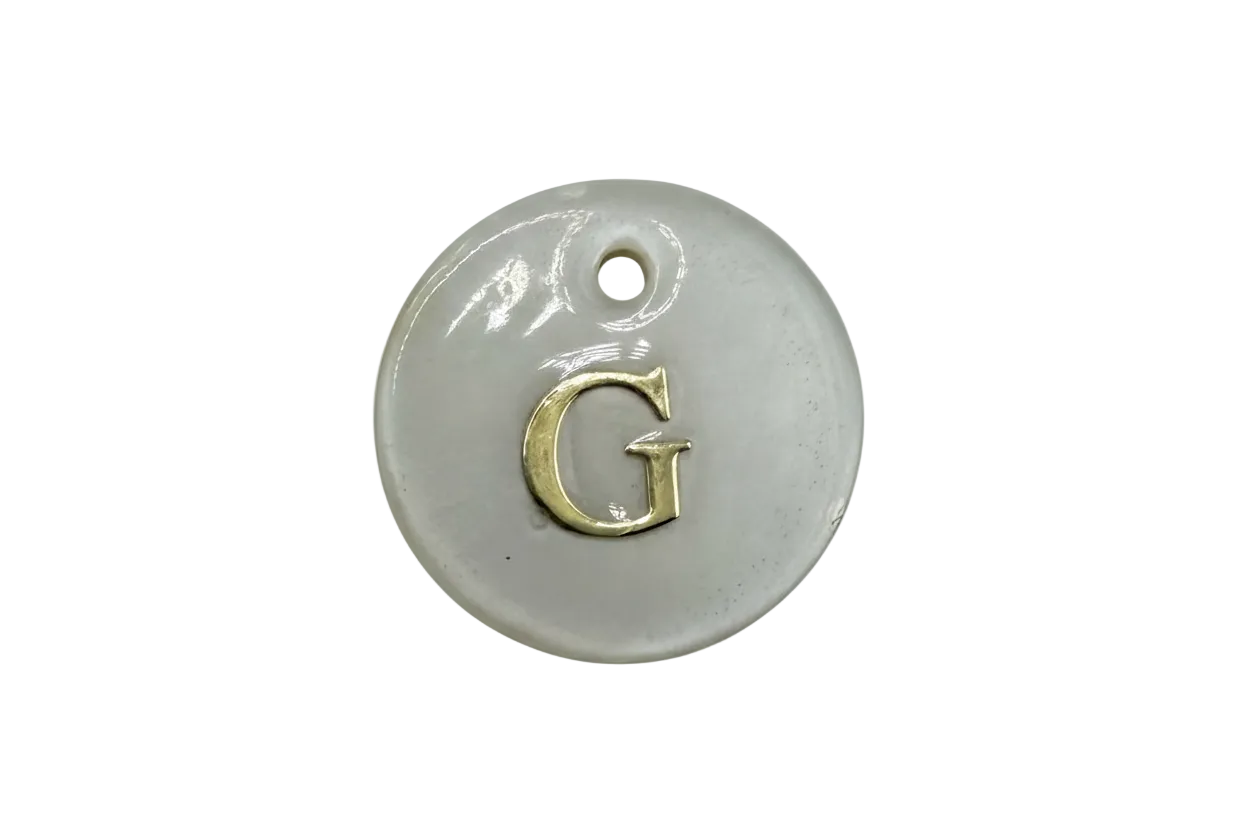 Glossy white round disc with raised gold letter G