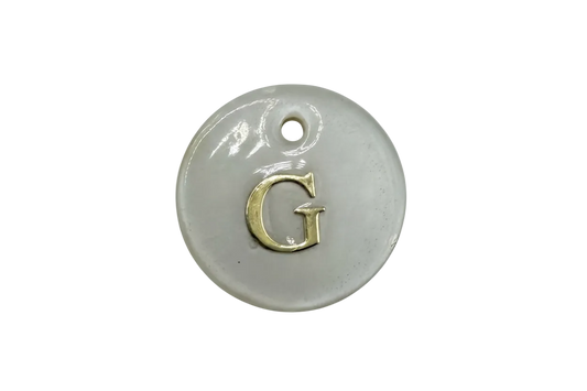 Glossy white round disc with raised gold letter G