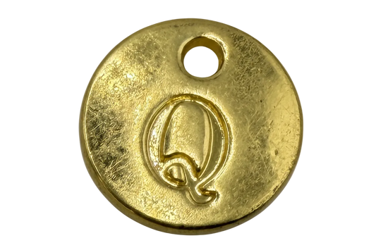 Round gold disk with engraved letter Q and textured finish