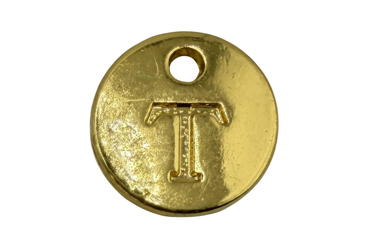 Round gold disc with raised letter T and a small top hole, polished finish