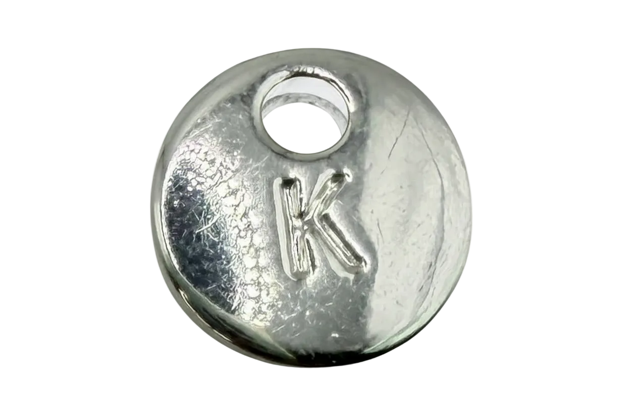 Round silver initial coin with raised letter K