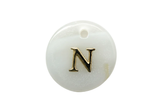 Glossy white round disc with raised gold serif letter N and black accent