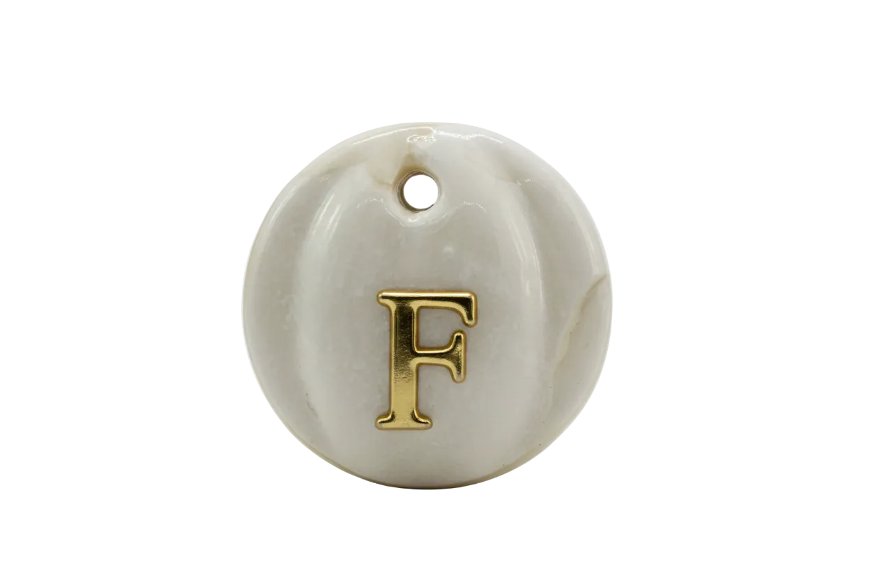 Glossy white round medallion with raised gold letter F