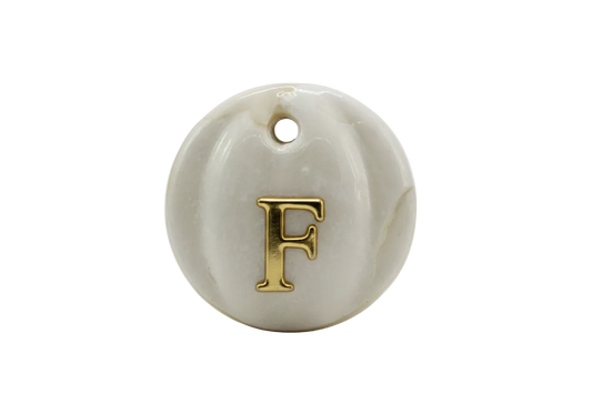 Glossy white round medallion with raised gold letter F