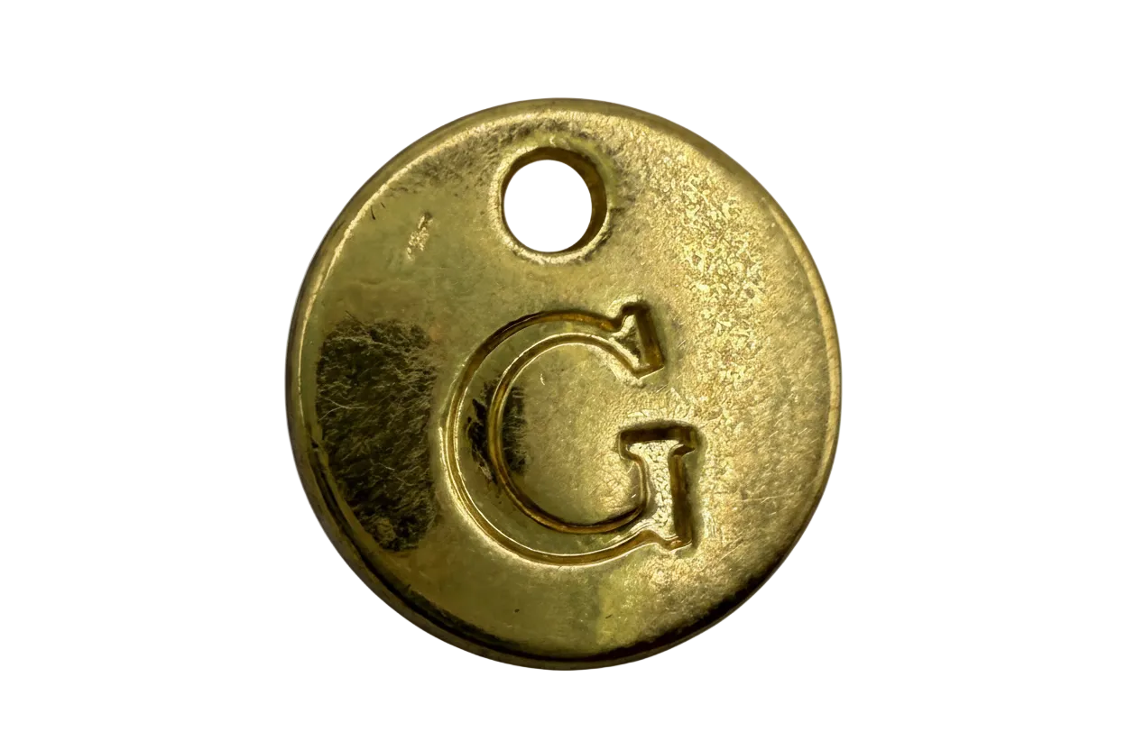 Gold round initial G coin disc with a small white gem accent