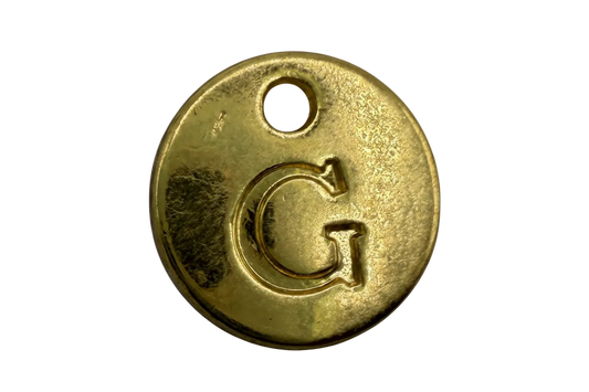 Gold round initial G coin disc with a small white gem accent