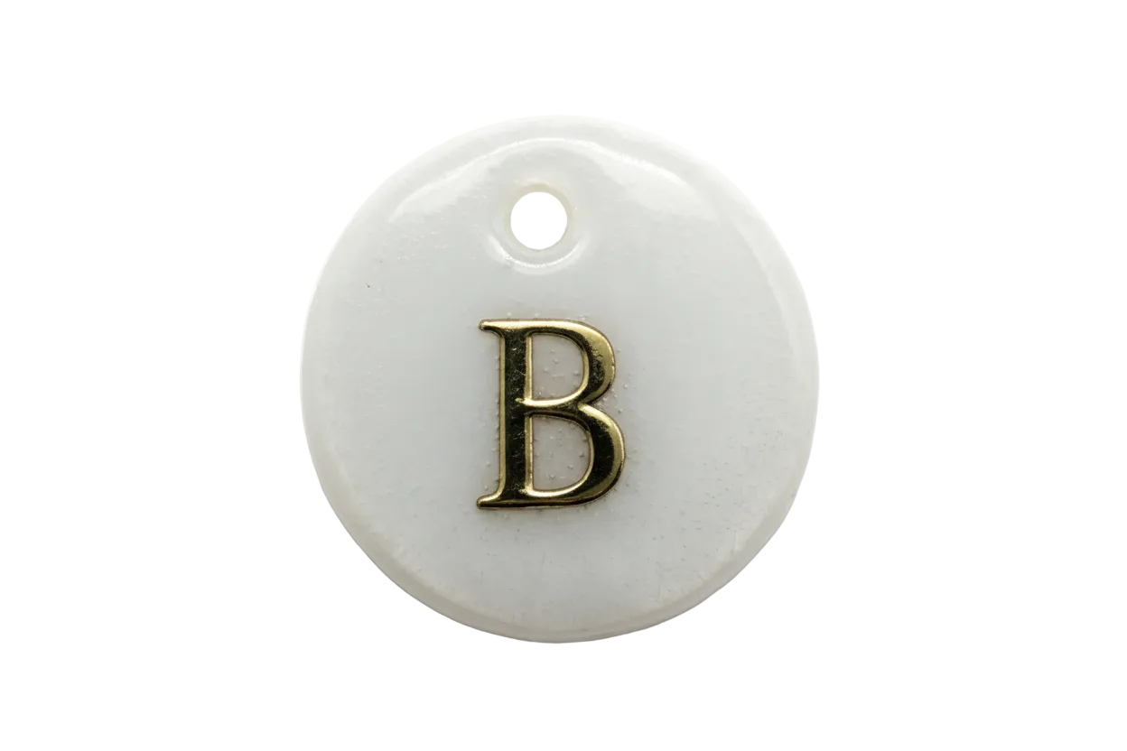 Iridescent pearl-white round disc with raised gold letter B