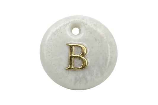 Glossy marbled white round disc with raised gold letter B