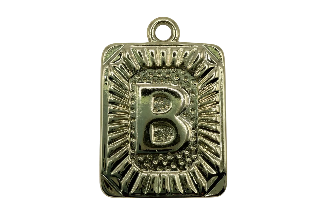 Gold rectangular initial B tablet with raised letter and textured sunburst border