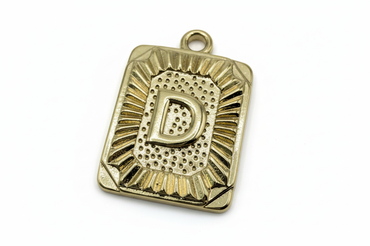 Gold rectangular plaque with raised letter D and sunburst-textured border
