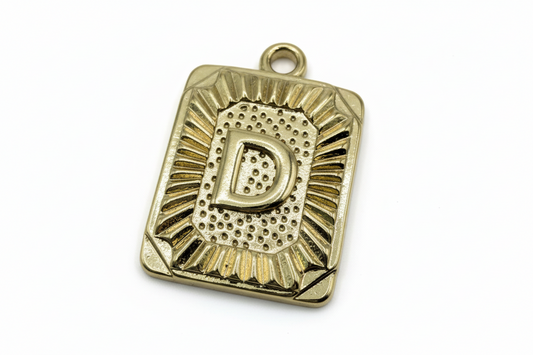 Gold rectangular plaque with raised letter D and sunburst-textured border